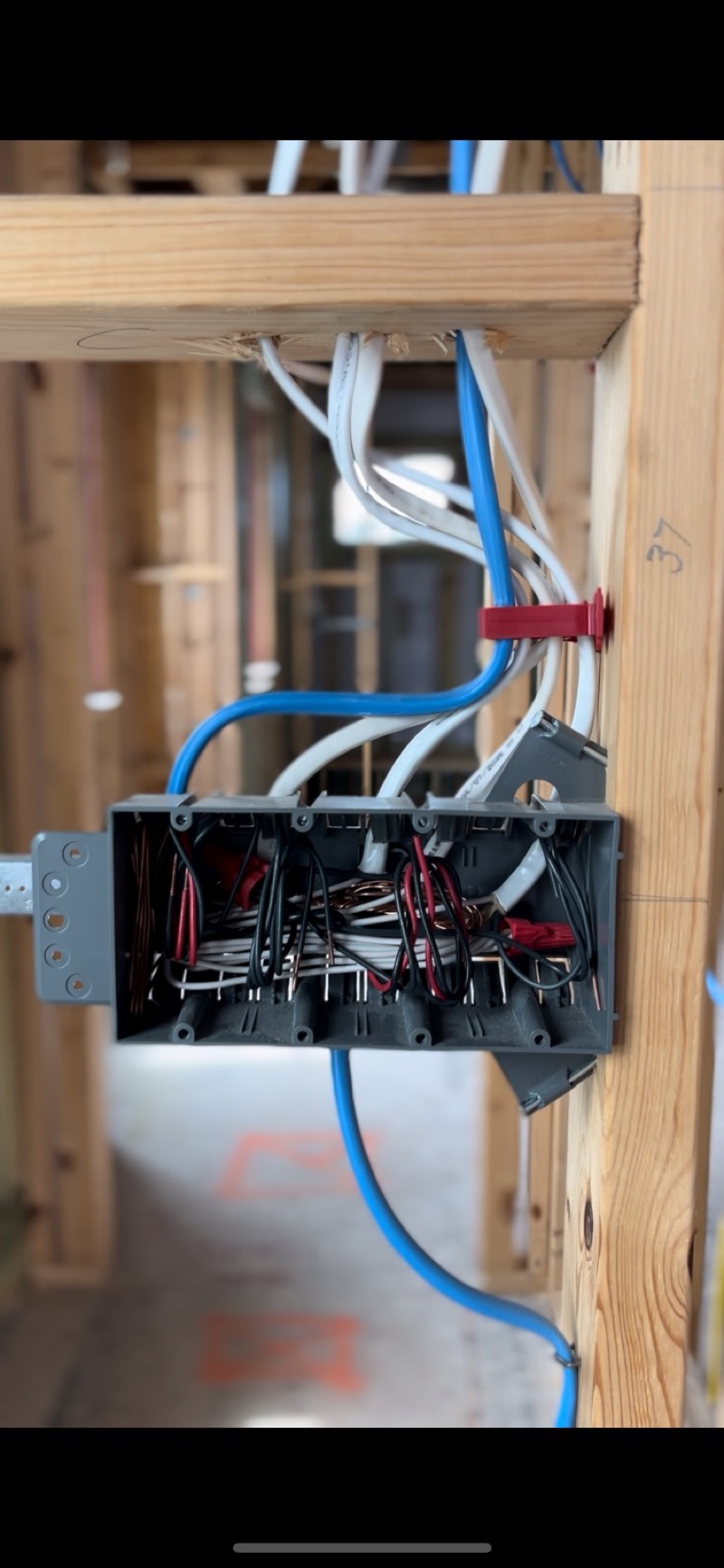 Junction box with blue and white wiring in wall framing during new construction